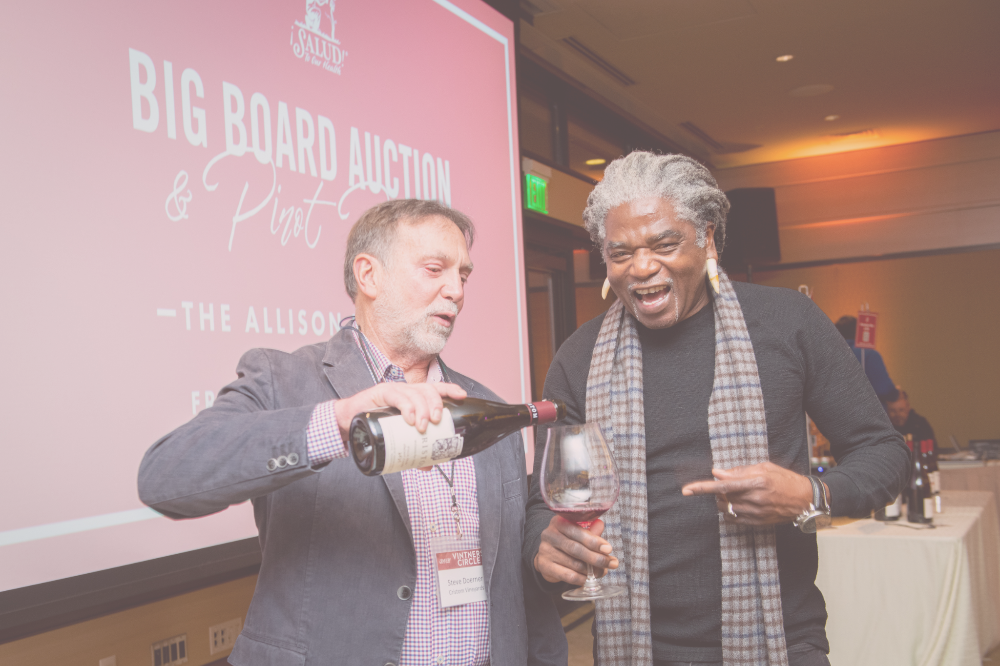 Man pouring wine into wine glass being held by another man